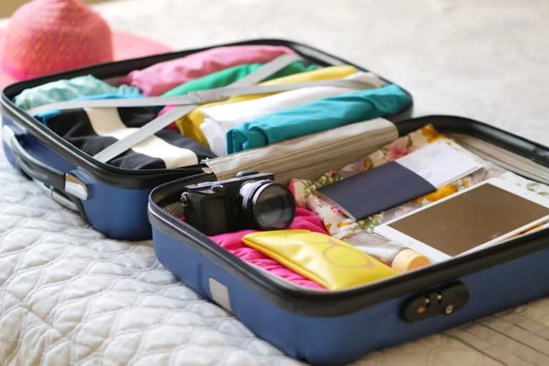 Open suitcase packed with clothes and passport ready for departure