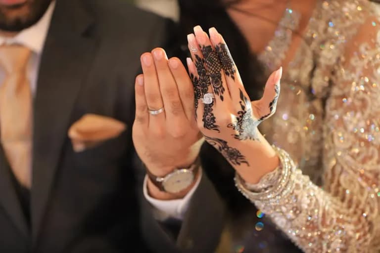 Couple's hands with wedding rings and henna